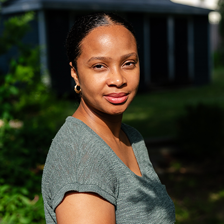 Arielle has cinnamon skin and dark brown hair and is looking directly into the camera.